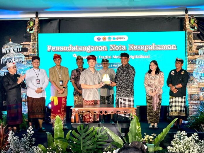 Head of GoPay Merchants Haryanto Tanjo, Bandesa Adat Kesiman I Ketut Wisna (di depan memegang plakat) (belakang dari ki - ka)) Direktur Pengawasan Lembaga Jasa Keuangan Kantor OJK Provinsi Bali Adityo Pamudji, Kepala Tim Pengawasan Sistem Pembayaran dan Pengelolaan Uang Rupiah Kantor Perwakilan Bank Indonesia Provinsi Bali, I Nyoman Agus Wirya, Bandesa Adat Tumbak Bayuh I Putu Sudiana, Bandesa Adat Sanur Ida bagus Sudiraharja, Audrey P. Petriny, dan AKBP (Purn) Putu Suprama (Panyarikan Utama Pasikian Pacalang Bali) dalam acara penandatanganan nota kesepahaman “Melestarikan Tradisi Melalui Digitalisasi”